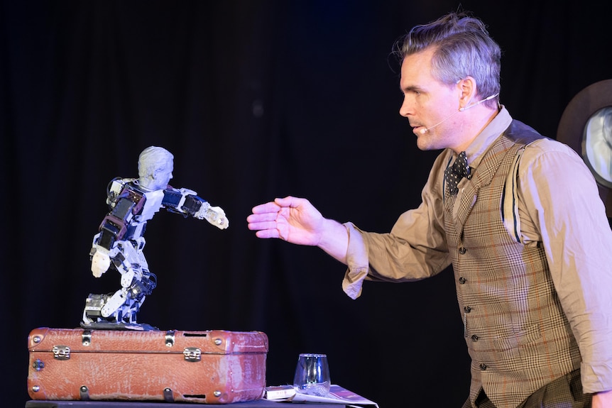 A man interacts with a small robot on stage