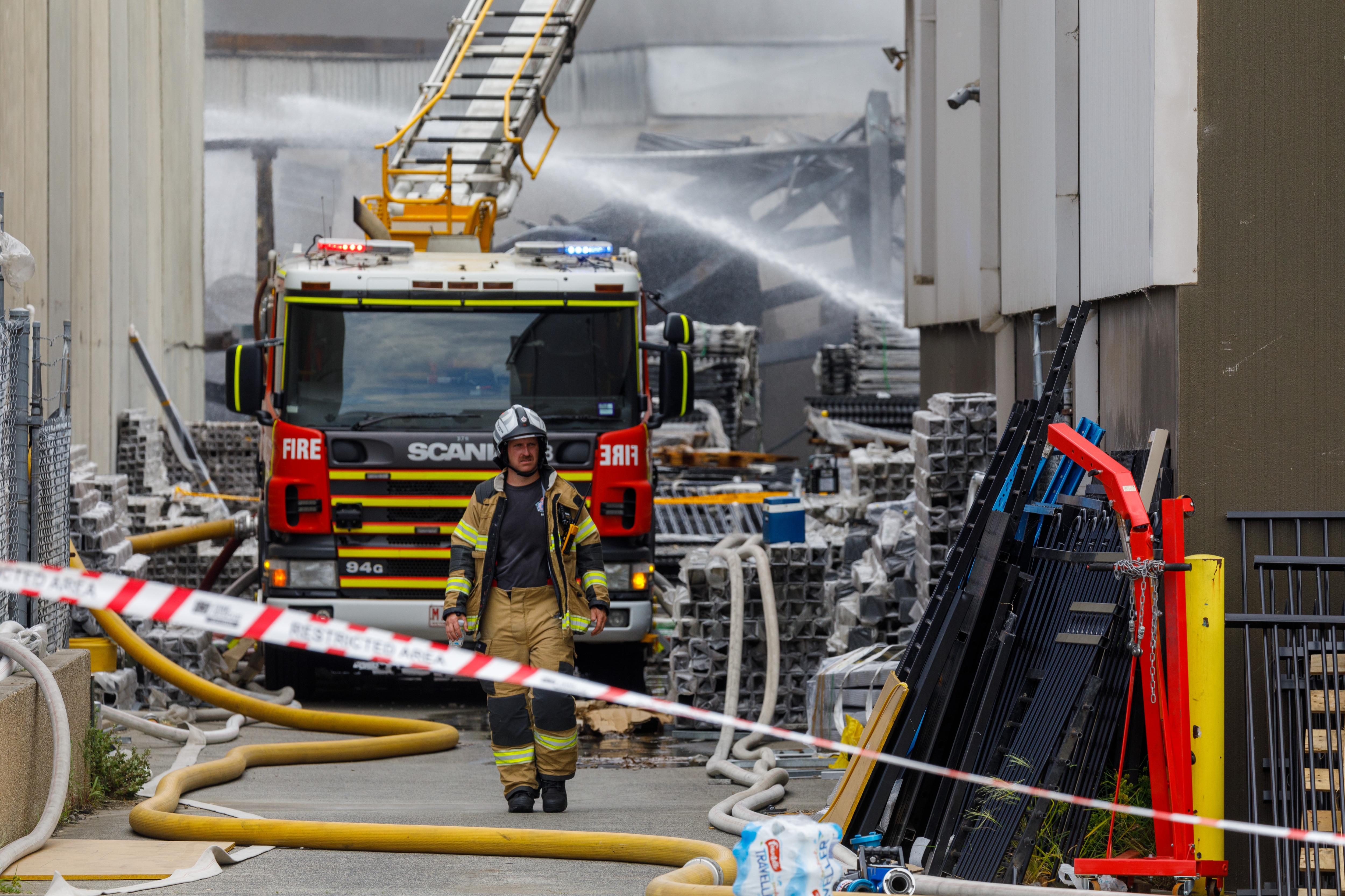 A firefighter walks away from a taped-off burnt and smoking building.