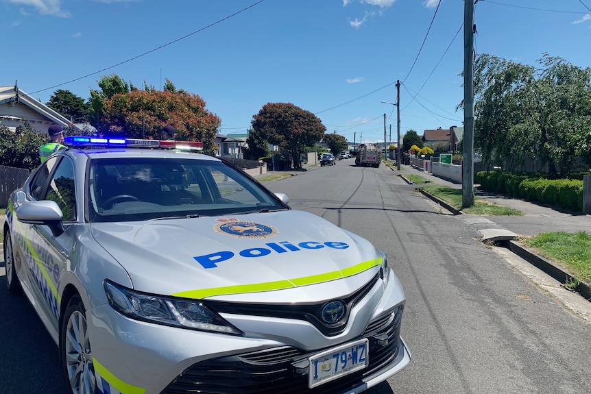 A police car blocks a suburban street