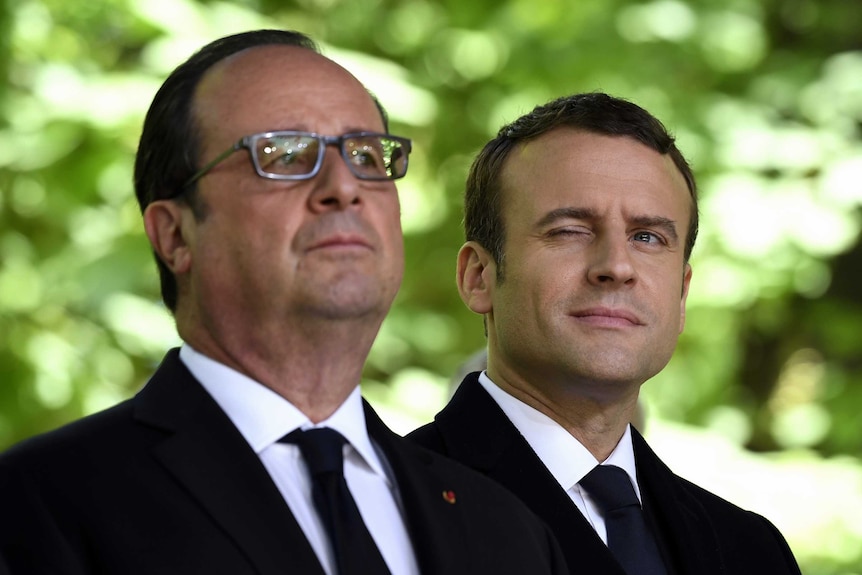 Emmanuel Macron winks as he stands beside outgoing French President Francois Hollande.