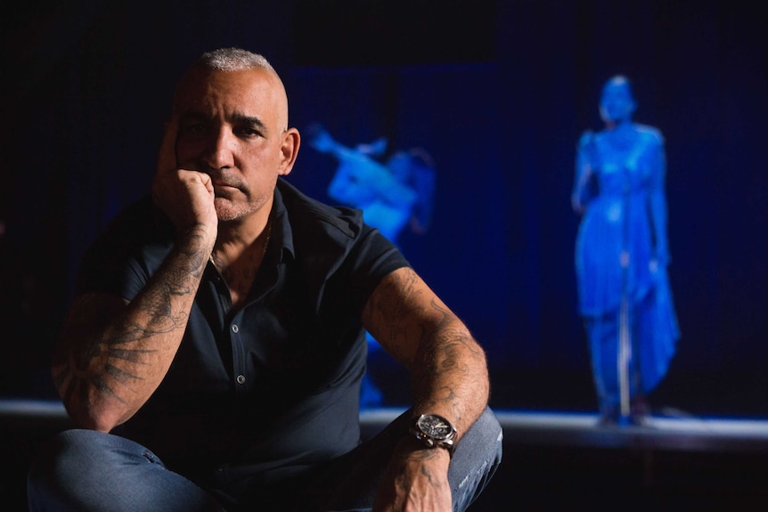 Alki David poses for a photo with a holographic image behind him
