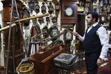 Man stands in a room with hundreds of clocks.