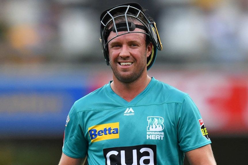 A Brisbane Heat batsman smiles with his helmet raised on top of his head during a BBL match.