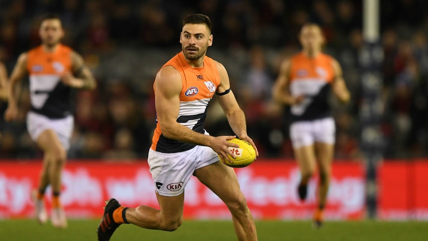 A man playing AFL wearing an orange shirt