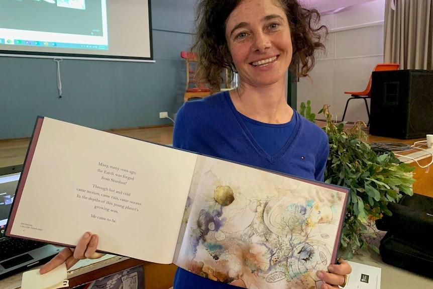 Aviva Reed holding up her book of illustrations