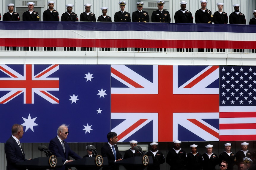 Anthony Albanese, Joe Biden and Rishi Sunak speak at lecturns underneath each of their country's flags