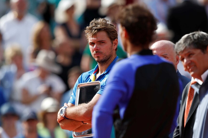 A disappointed Stan Wawrinka looks on as Rafael Nadal speaks at the presentation ceremony.