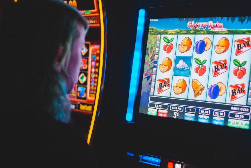 A woman playing a poker machine.