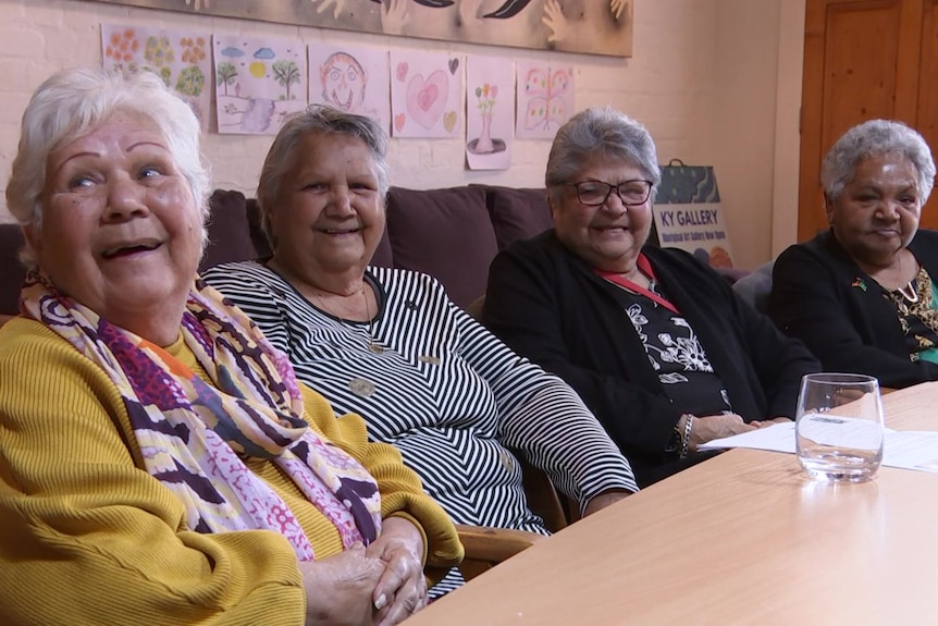 Four Aboriginal women seated alongside each other at a table