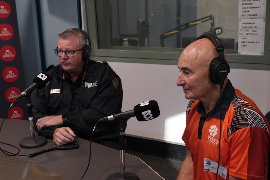 two men sitting inside a radio studio, speaking into microphones