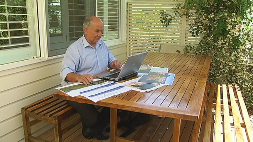 Dr Philip Pells sits at outdoor table looking at a laptop
