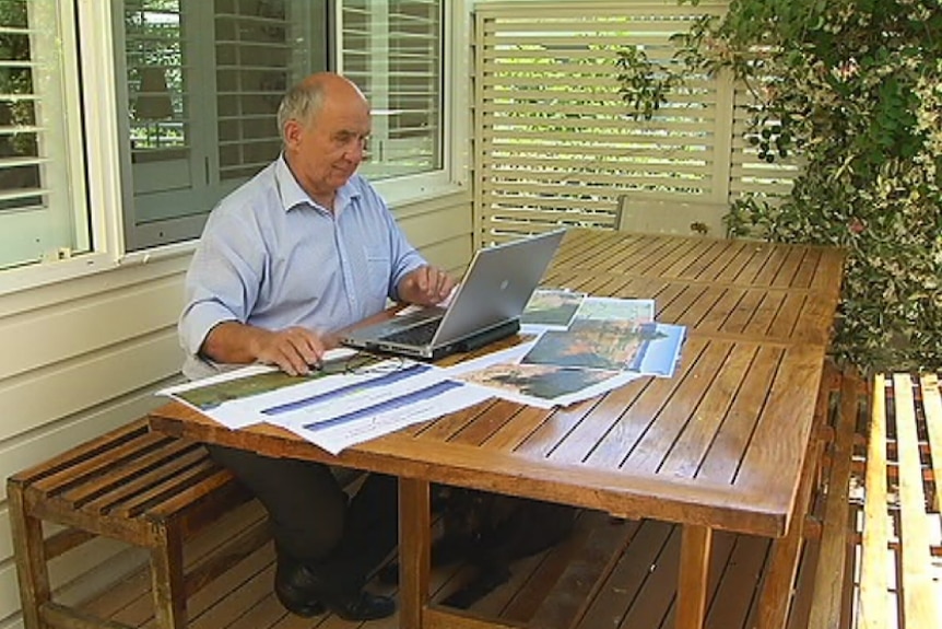 Dr Philip Pells sits at outdoor table looking at a laptop