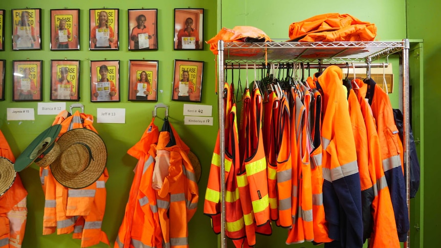 high vis jackets hanging on rail with bright green wall in background.