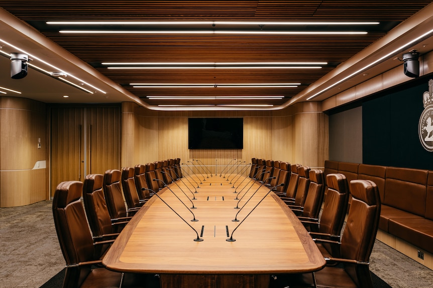 Large oval wood table surrounded by multiple leather chairs.