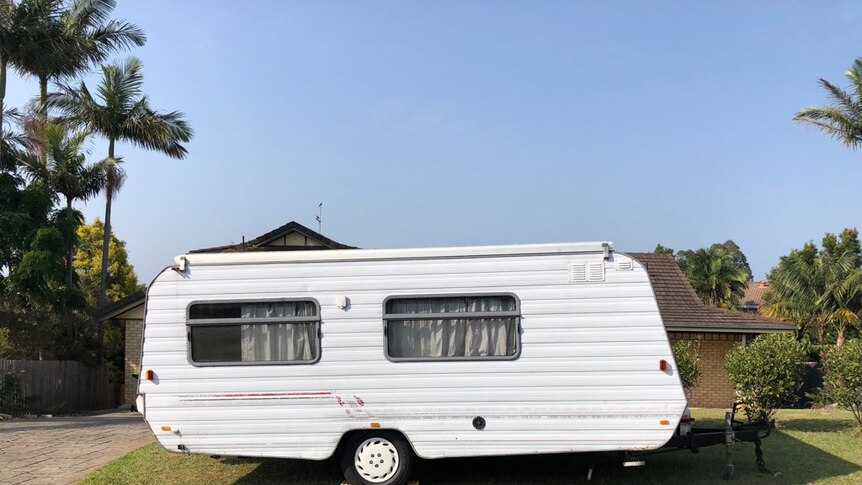 A white caravan parked outside a house in Coffs Harbour.