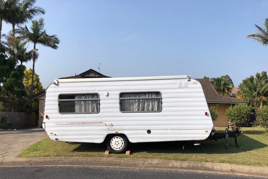 A white caravan parked outside a house in Coffs Harbour.