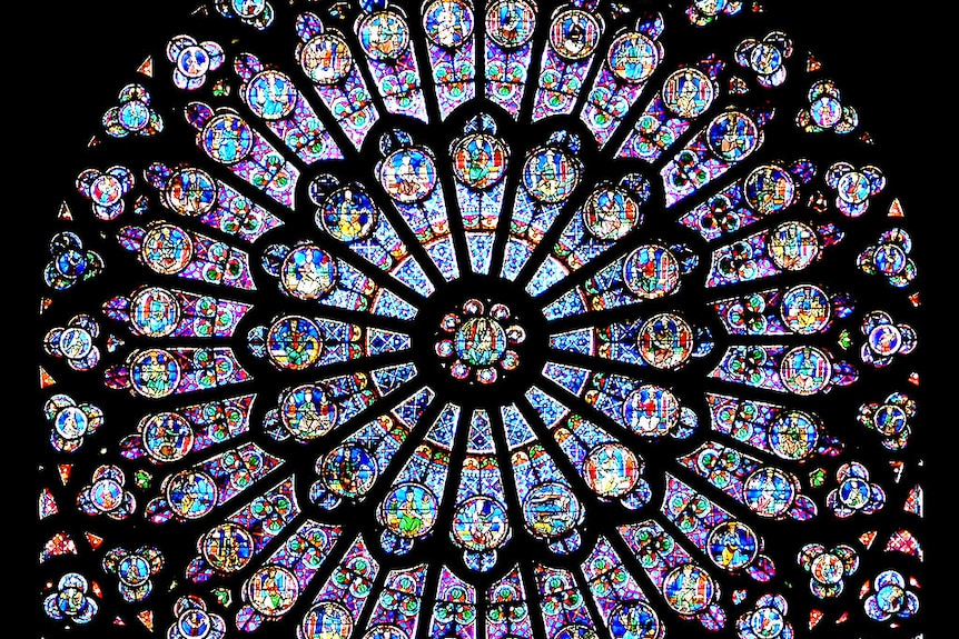 Notre Dame's rose windows lit up from behind.