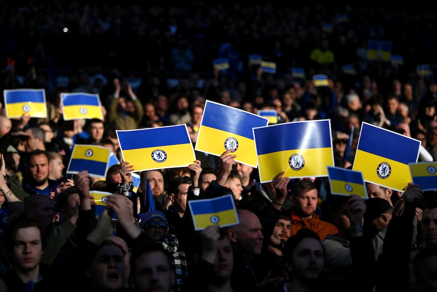 A crowd holding banners displaying the Ukraine flag