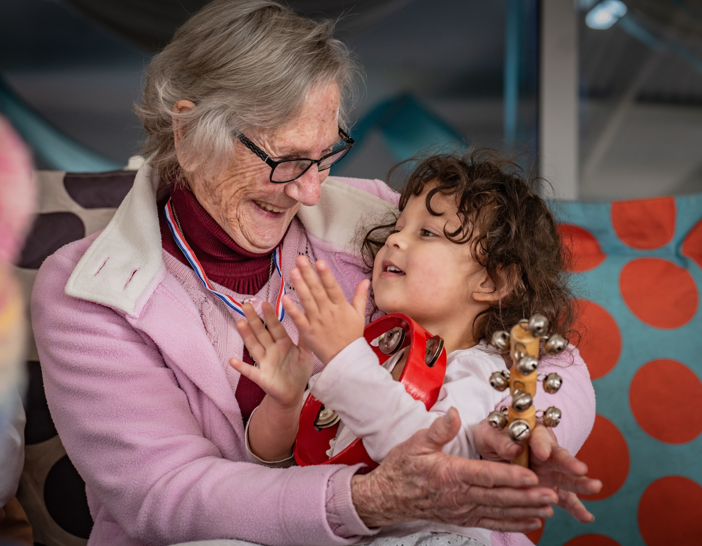 An elderly lady sits with a toddler on her lap. 