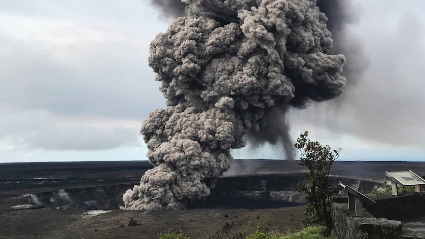Ash column rises from the crater at Kilauea in Hawaii. It is very tall and dark.