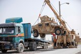 A US Army HUMV is loaded onto the back of a large truck