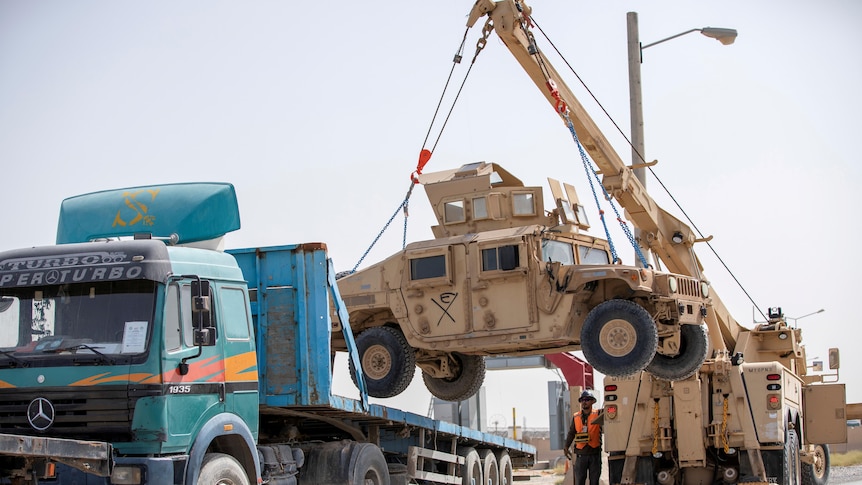 A US Army HUMV is loaded onto the back of a large truck