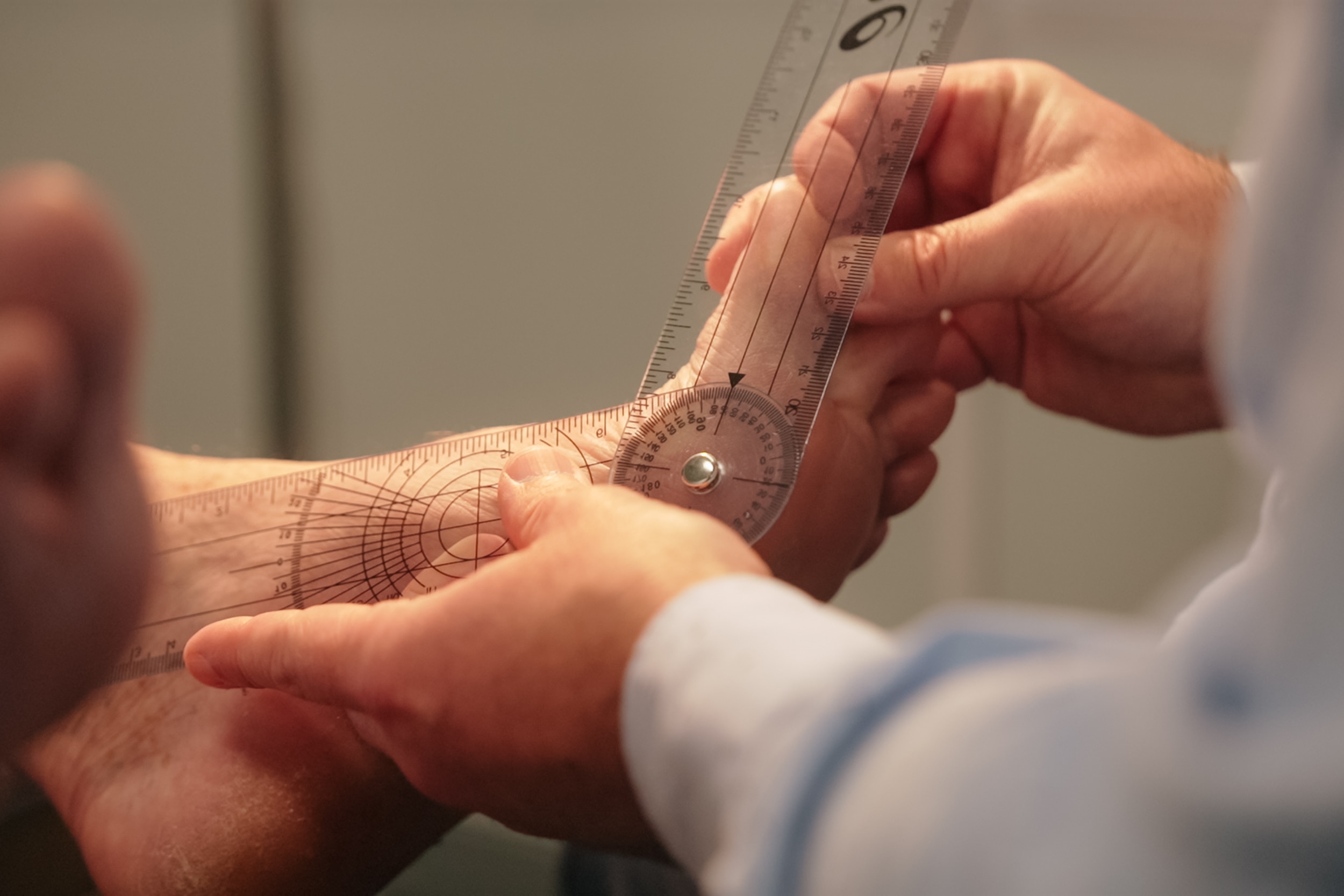 A person uses a ruler to measure someone's feet.