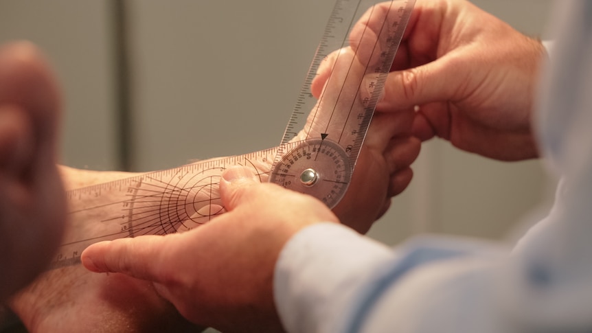 A person uses a ruler to measure someone's feet.