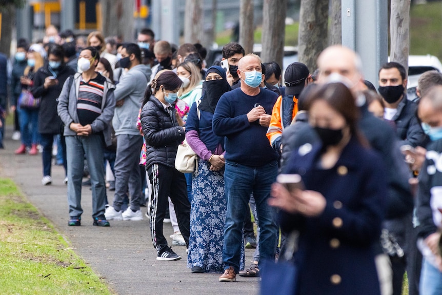 A long outdoor queue of people wearing masks