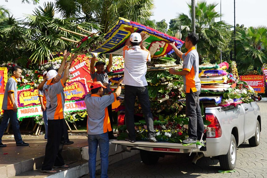 Workers help to deliver and arrange the flower boards for display.