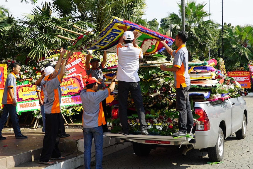 Workers help to deliver and arrange the flower boards for display.