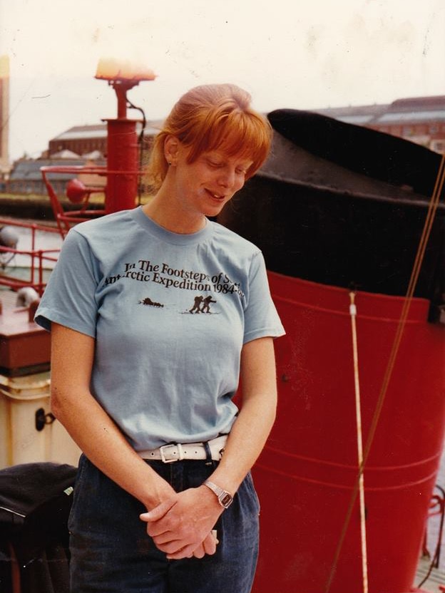 Woman with flaming red hair wearing 80s attire on a boat.