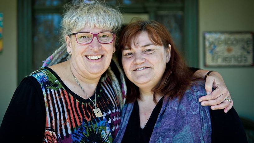Two women - one with glasses with arm around the other