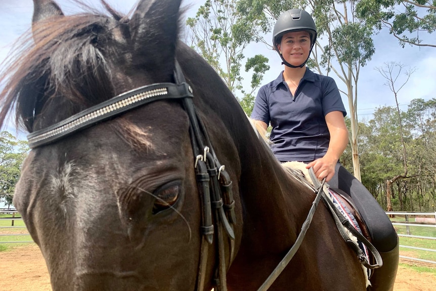 Maddie Nelson sits on her horse, Pablo Cruize, wearing a riding helmet