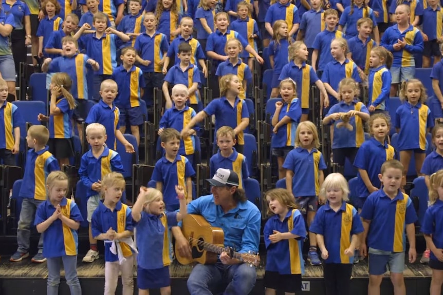 man with guitar surrounded by kids