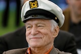 Playboy founder Hugh Hefner wears a boat captain's hat while smiling.