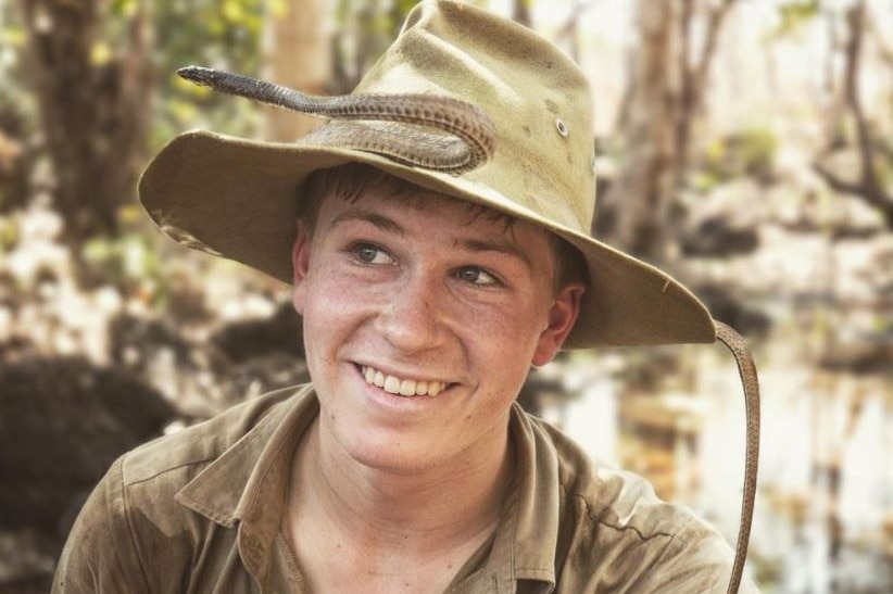 Teenage boy in khaki uniform with snake on his wide-brimmed hat