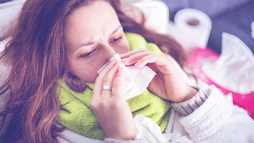 Woman lying in bed blowing her nose