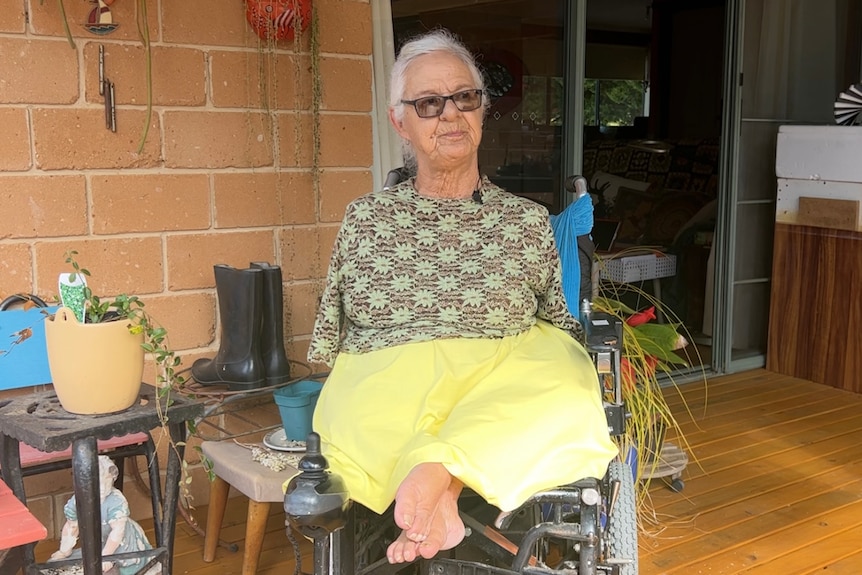 Woman in a grey shirt in a wheelchair with a yellow blanket on her lap.