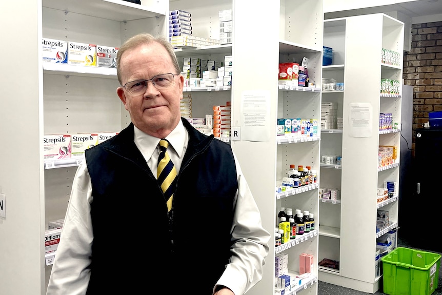 A man stands in front of medicine cabinets.