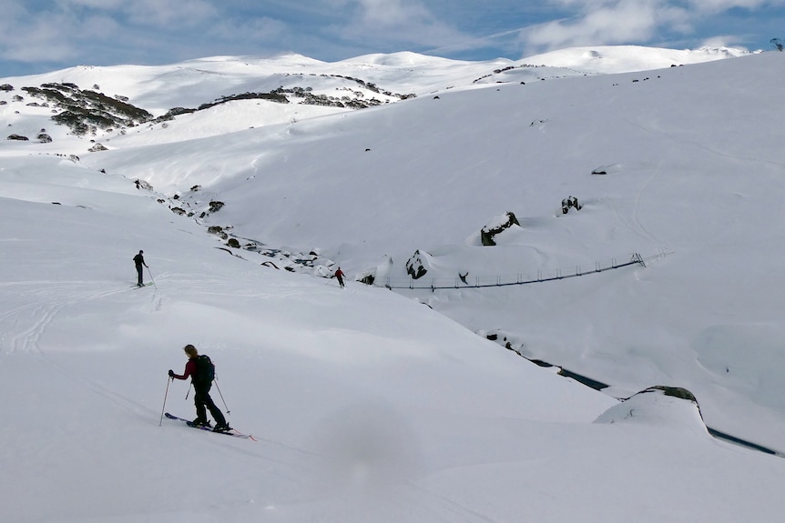 Skiers make their way across a snowy mountain.