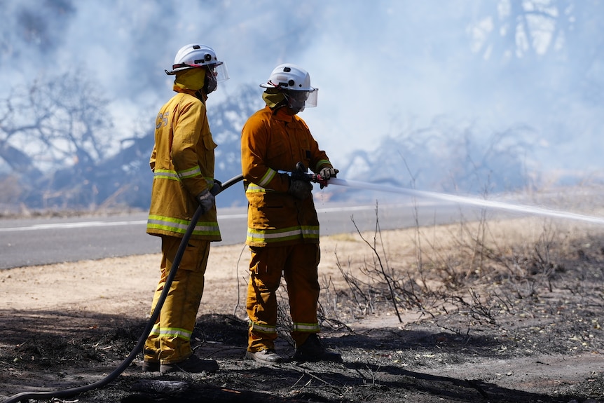 Country Fire Service firefighters hose down a fire.