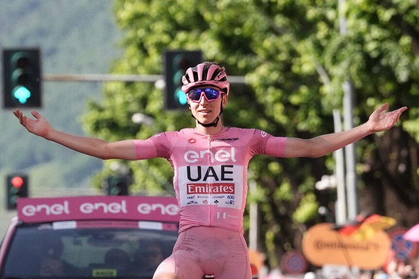 Tadej Pogacar holds out his hands on his bike