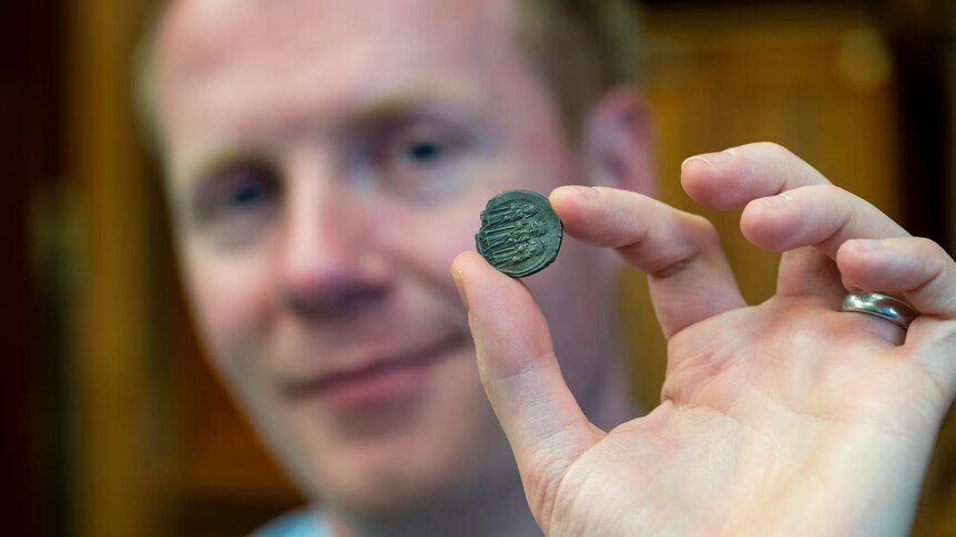 a man holds an old coin