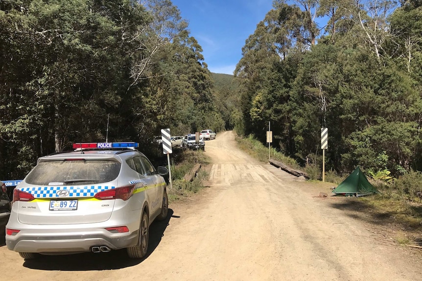 A police car parked near a tent in Tasmania bush.