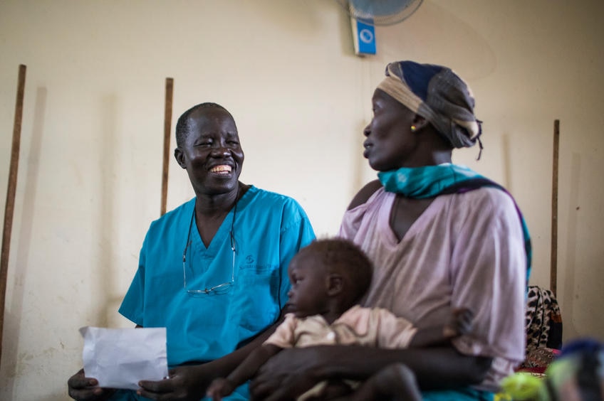 Dr. Evan Atar Adaha sits with a refugee from Sudan and her malnourished son