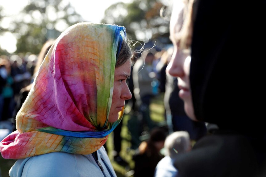 Two women don colourful head scarves during a remembrance service at Christchurch