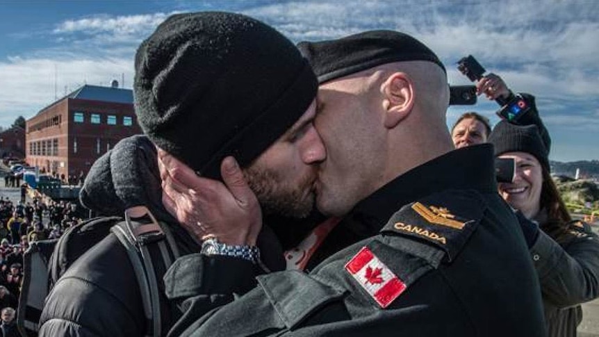 An image of a serviceman kissing his partner