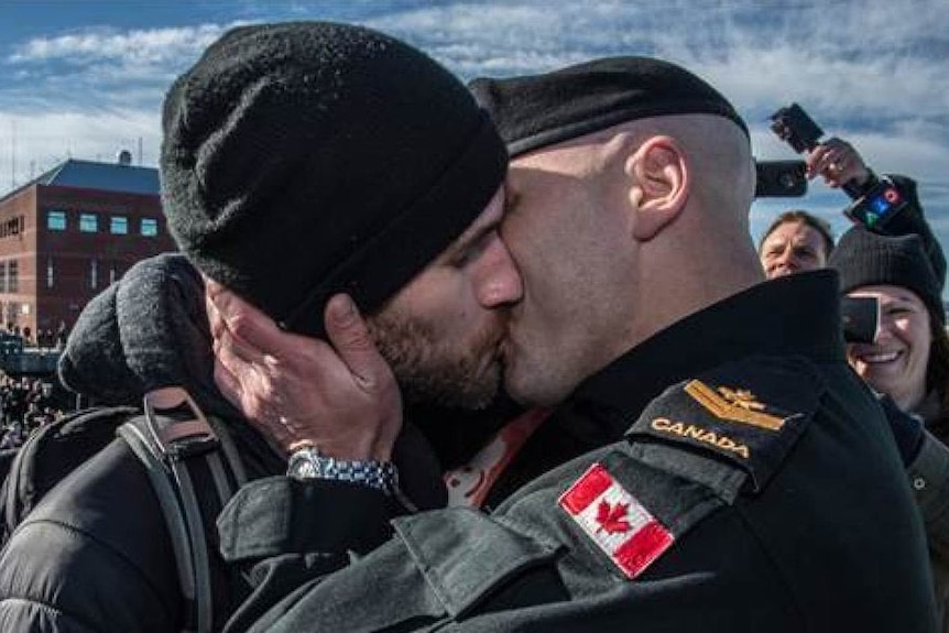 An image of a serviceman kissing his partner