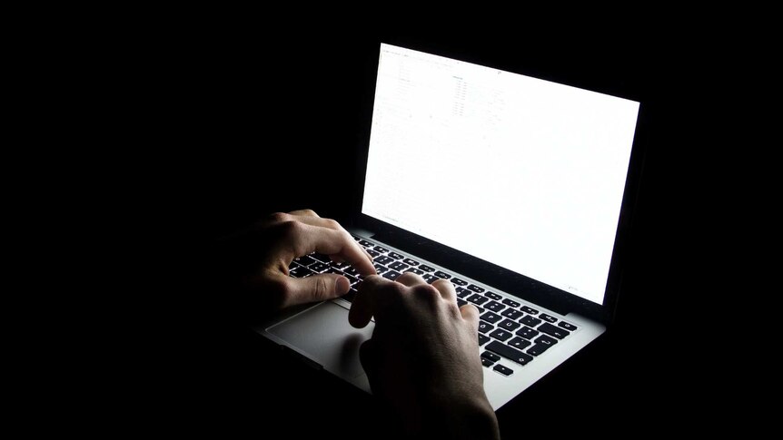 person typing on computer in the dark